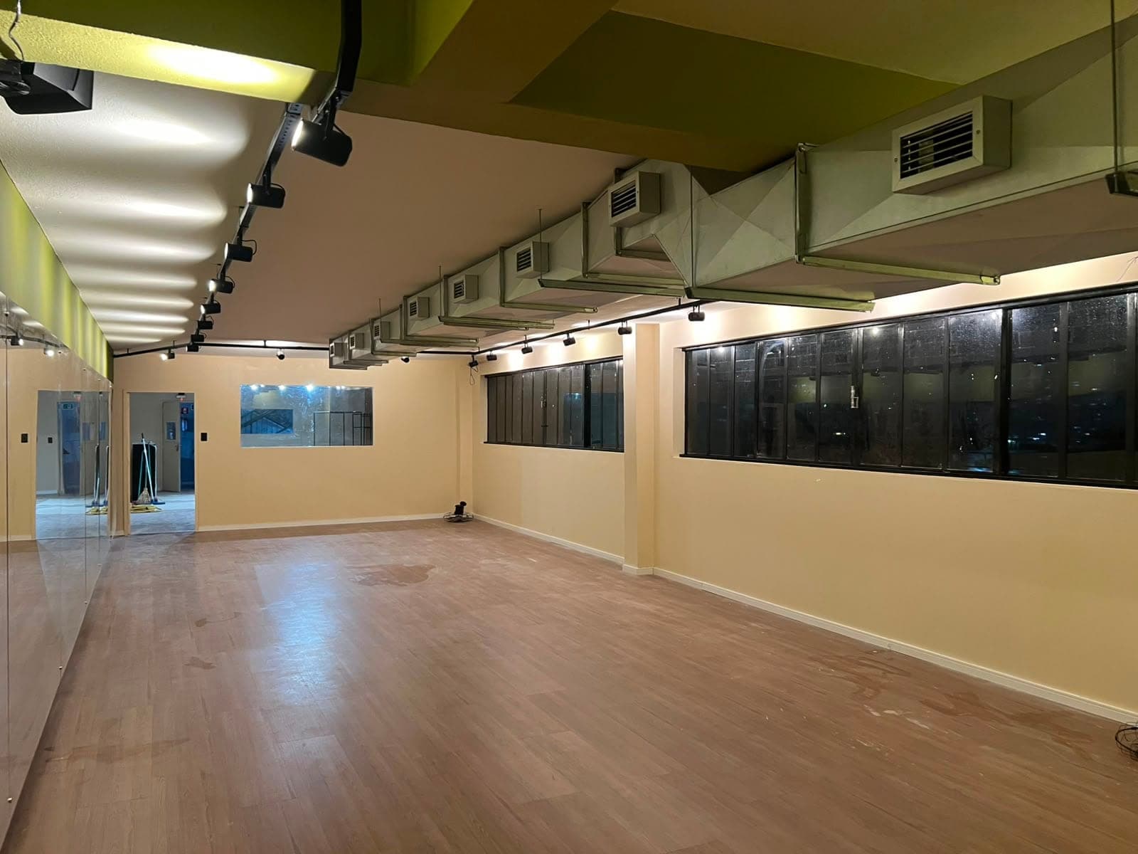 Vista da sala de hot yoga do Hikari, com janelas amplas e pé-direito alto.
